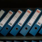 Neatly arranged blue office binders labeled with dates and names for organized storage.